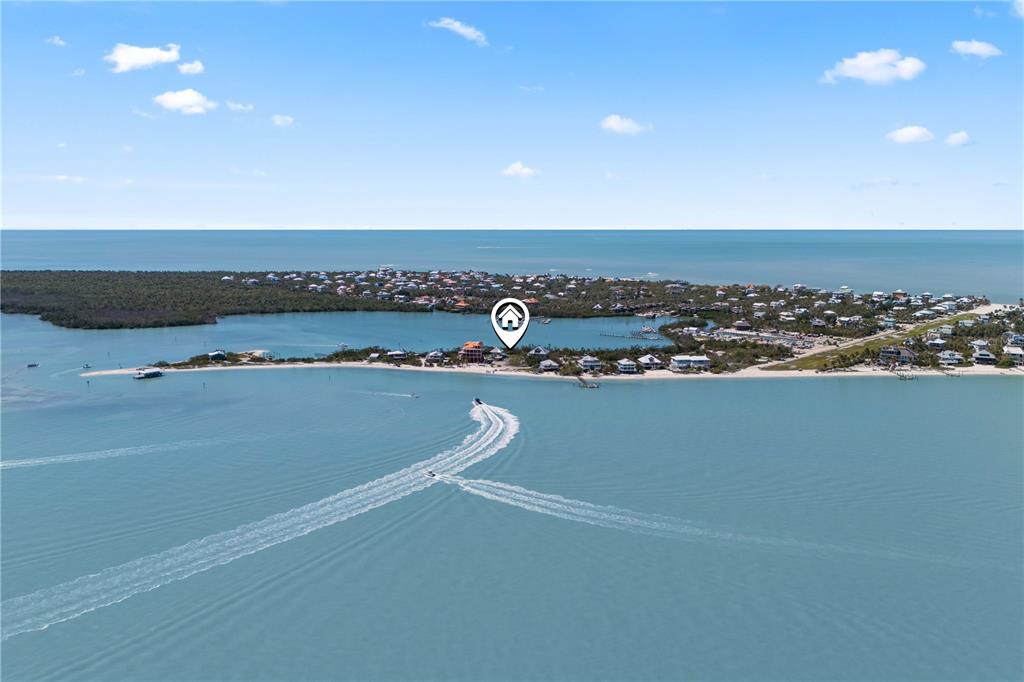 An aerial view shows a coastal community with a boat leaving a wake offshore — 4281 POINT HOUSE TRAIL, CAPTIVA, FL