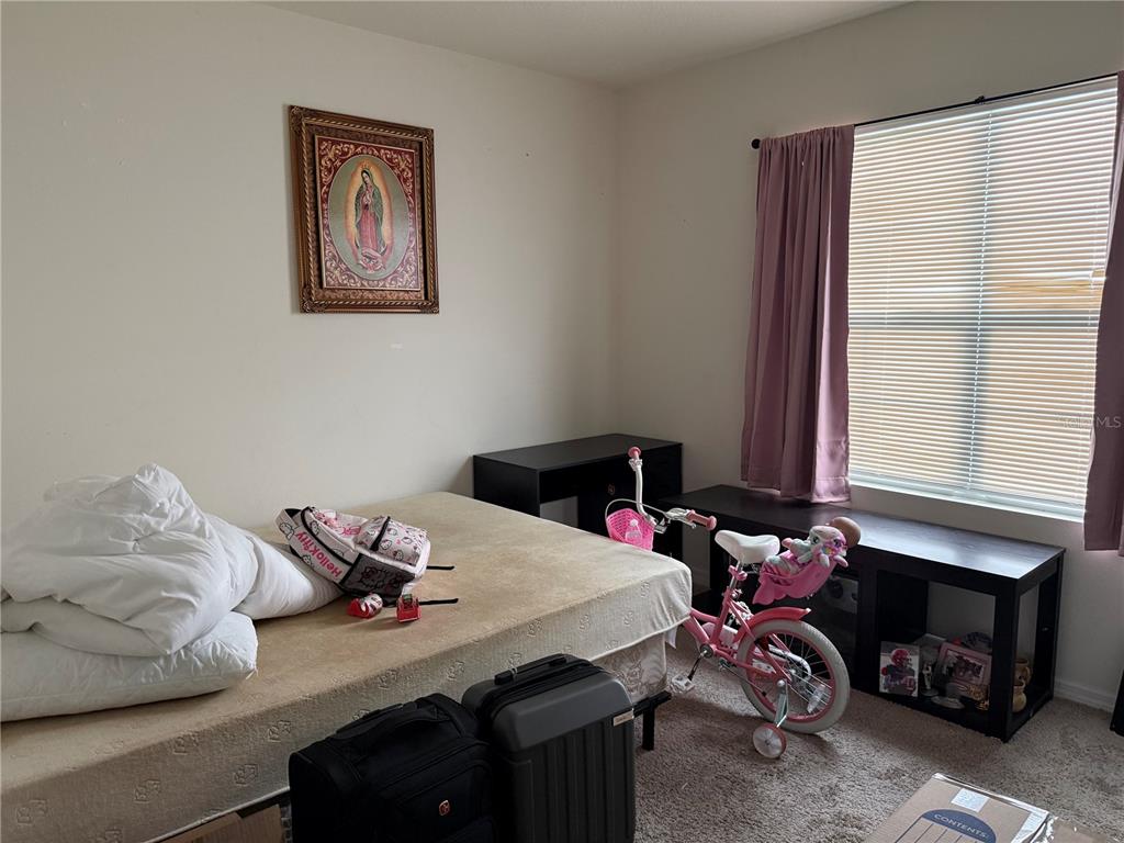 A bedroom features a bed, a bicycle, two suitcases, and a framed religious picture — 3597 YARIAN, HAINES CITY, FL