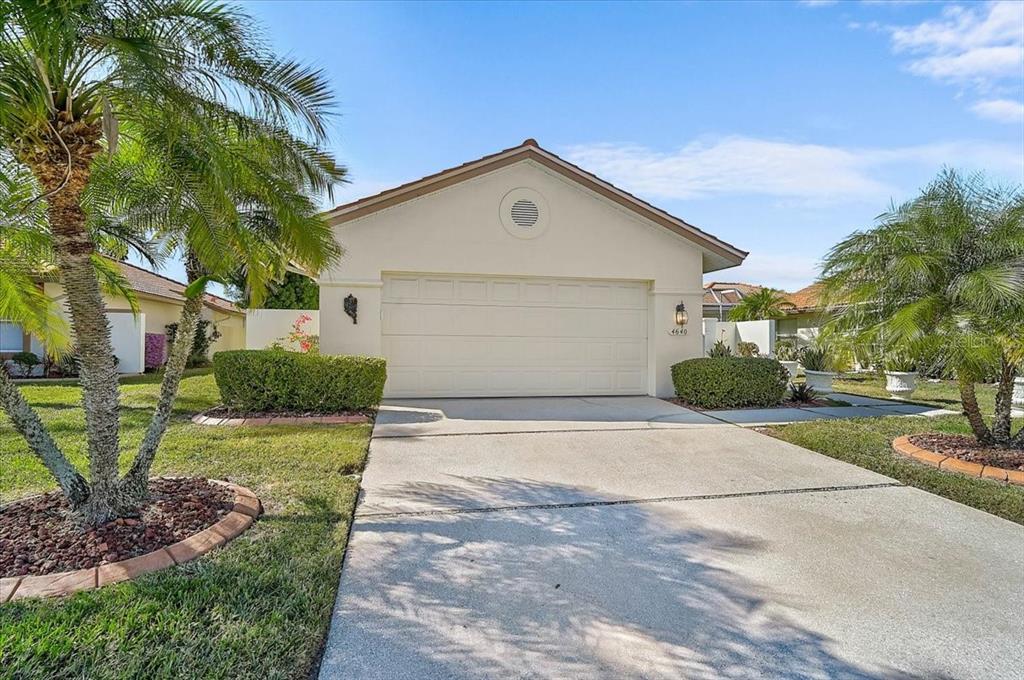 A single-story house with a beige exterior, a two-car garage, and palm trees in front — 4640 PERIDIA BOULEVARD E, BRADENTON, FL