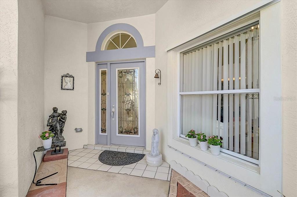 A front entryway features a light blue door with decorative glass, a transom window, and planters — 4640 PERIDIA BOULEVARD E, BRADENTON, FL