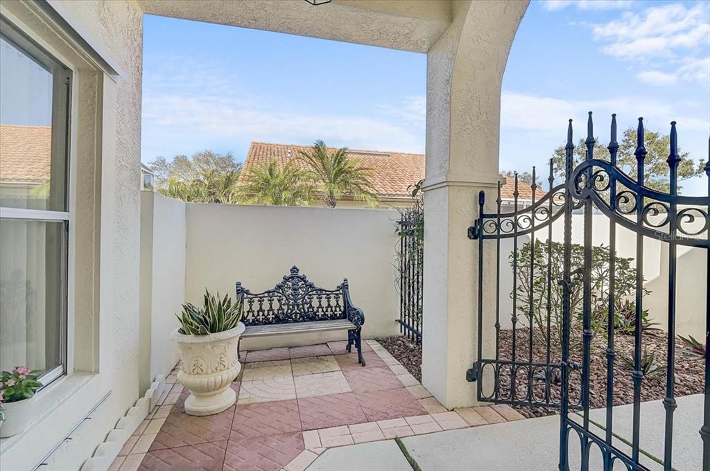 A small patio features a wrought iron bench, a potted plant, and a metal gate — 4640 PERIDIA BOULEVARD E, BRADENTON, FL