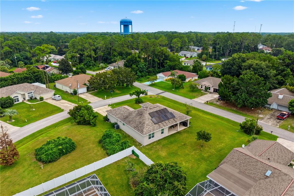 An aerial view shows a suburban house with solar panels on its roof and yard — 50 PEPPER LANE, PALM COAST, FL