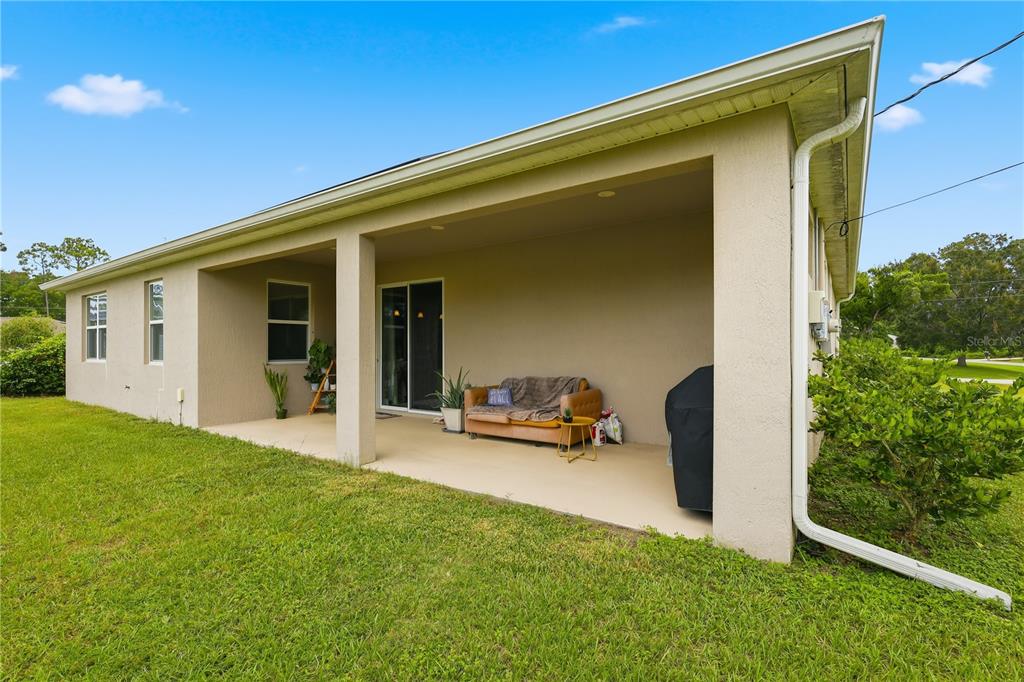 The rear exterior of a tan house features a covered patio and rooftop solar panels — 50 PEPPER LANE, PALM COAST, FL