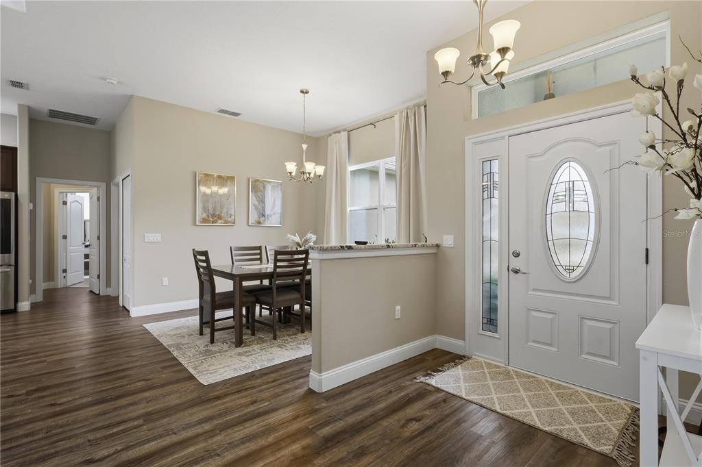 A dining area with a wood table and chairs sits beside a white front door — 50 PEPPER LANE, PALM COAST, FL