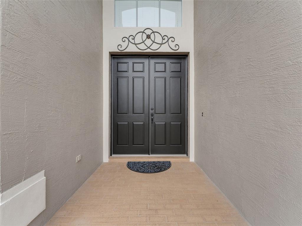 A front entryway features double black doors, a decorative metal accent, and a tiled floor — 1900 CARDAMON DRIVE, TRINITY, FL