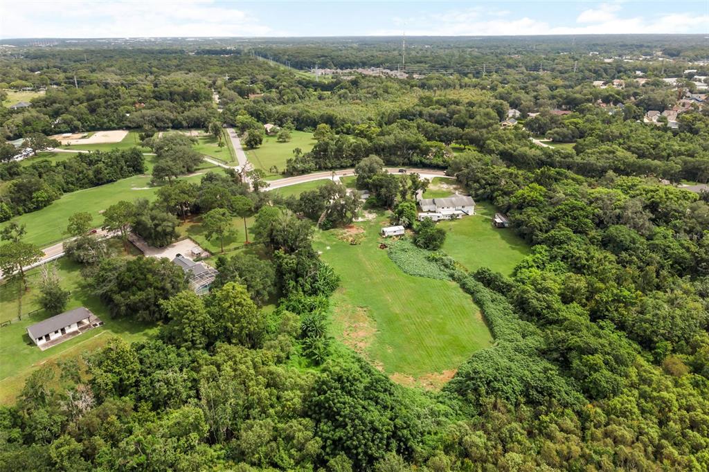 An aerial view shows a large grassy lot with a house, outbuildings, and surrounding trees — 250 LONGWOOD HILLS ROAD, LONGWOOD, FL