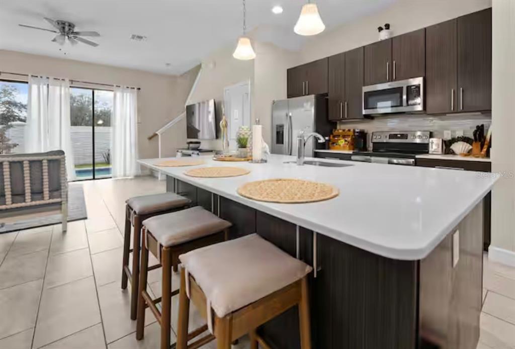 A modern kitchen features a large white island with bar stools and dark wood cabinetry — 192 VILLA DOMANI CIRCLE, DAVENPORT, FL