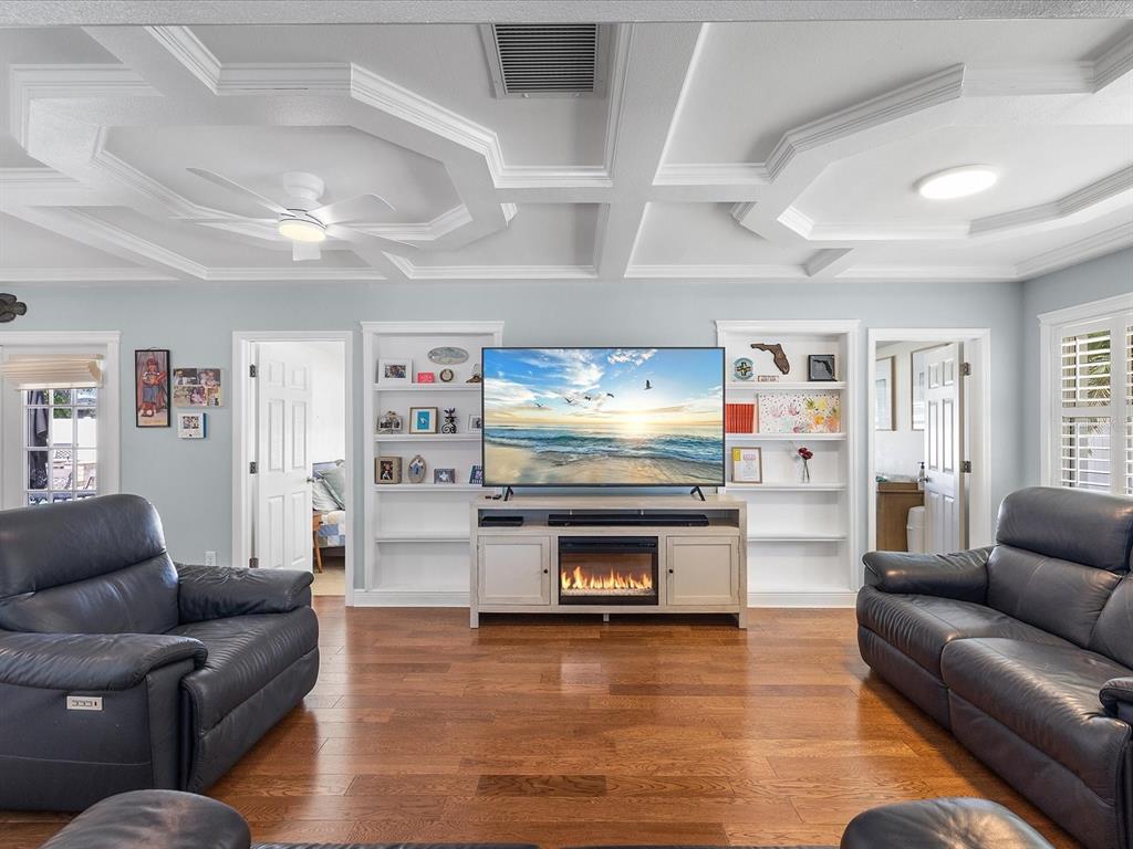 A living room features a coffered ceiling, hardwood floors, built-in shelving, and two leather sofas — 118 LIVE OAK LANE, LARGO, FL