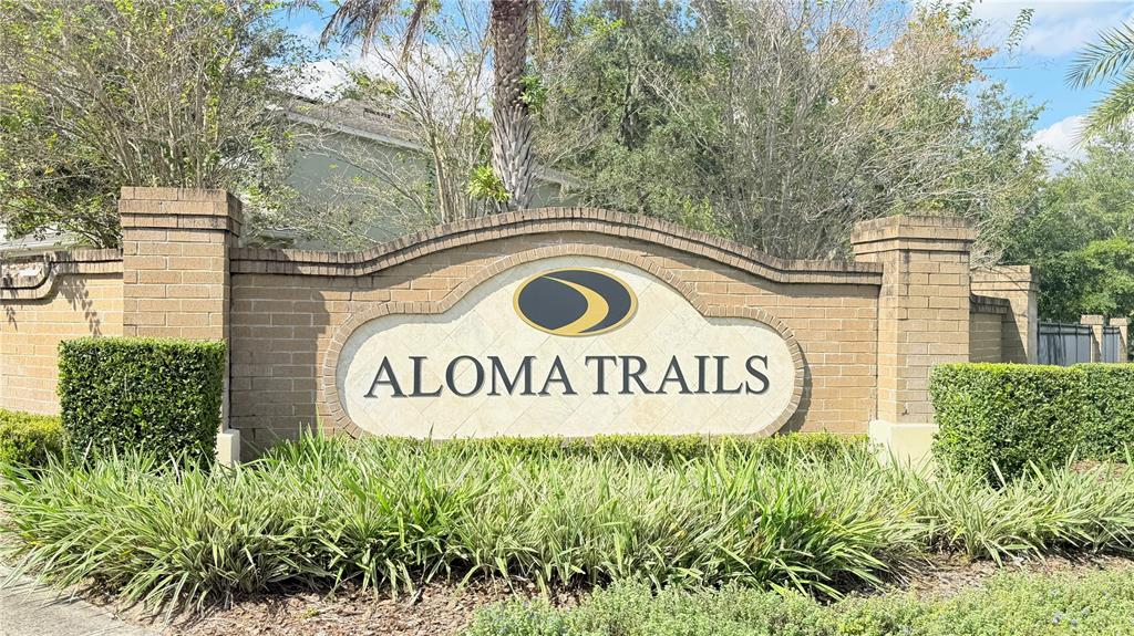 A brick monument sign for Aloma Trails stands in front of trees and landscaping — 7605 ALOMA PINES COURT, WINTER PARK, FL