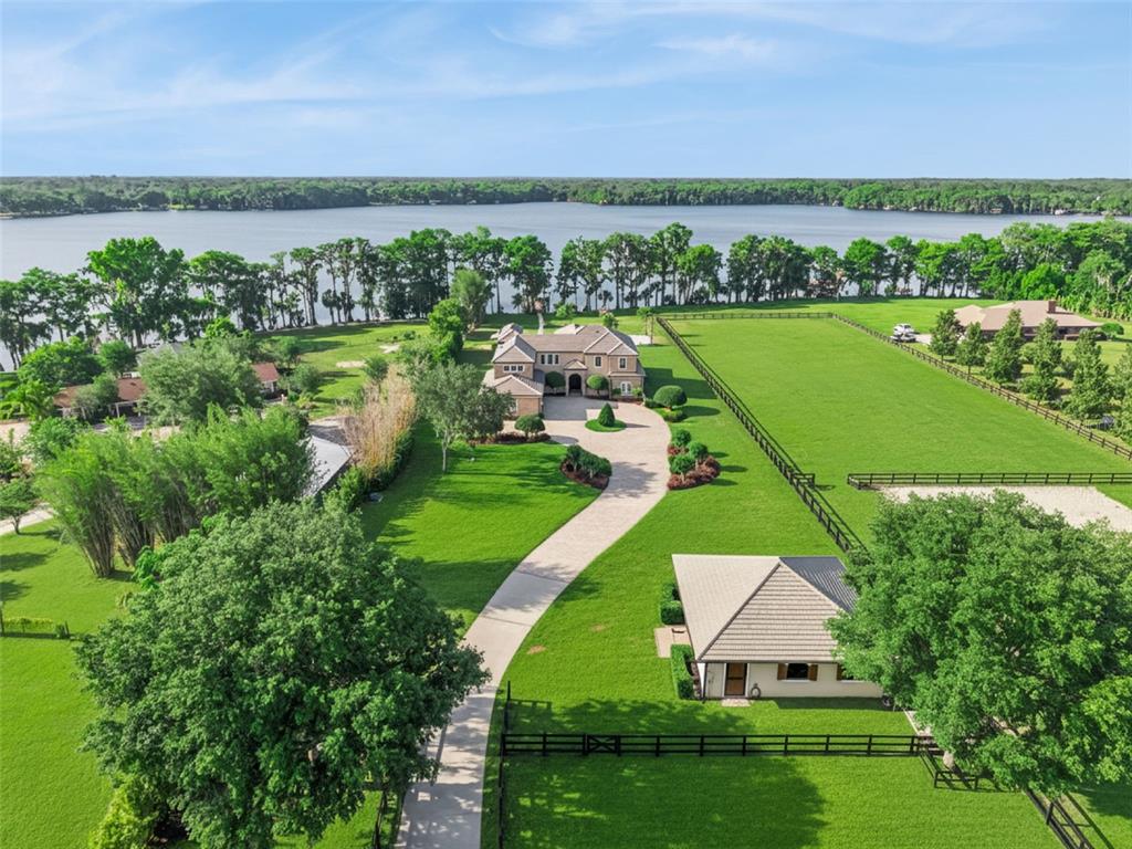 An aerial view shows a large house with a long driveway, expansive lawns, and a lake — 746 LAKE MILLS ROAD, OVIEDO, FL