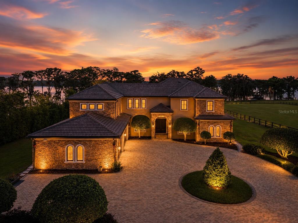 An aerial view of a two-story stone and stucco house with a circular paver driveway — 746 LAKE MILLS ROAD, OVIEDO, FL