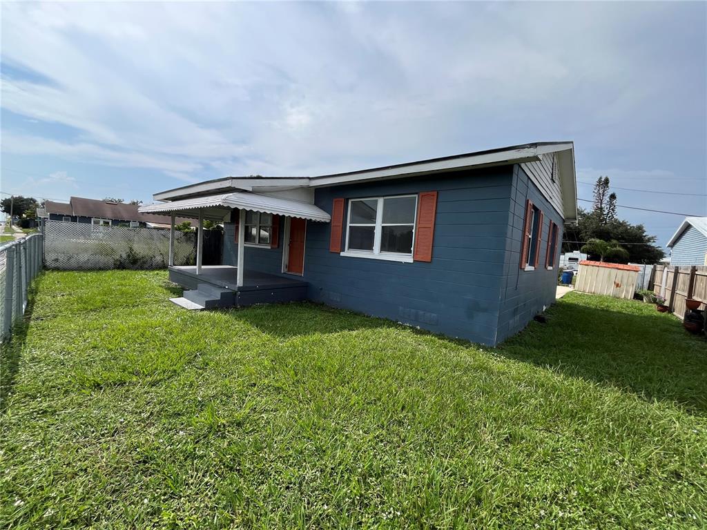 A blue house exterior features a covered porch, an orange front door, and red shutters — 1206 E CANAL STREET, MULBERRY, FL