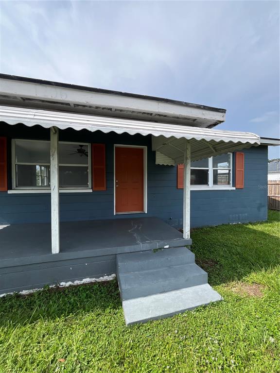 A blue house with a covered porch and a black wooden fence in the yard — 1206 E CANAL STREET, MULBERRY, FL