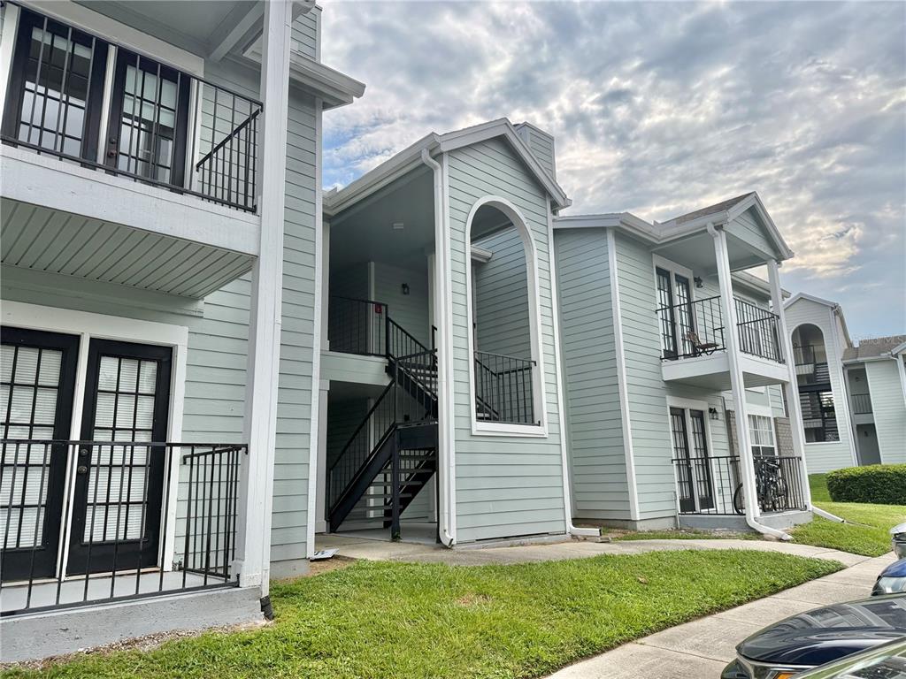 Exterior view of a multi-story apartment building with light green siding and black metal railings — 2550 N ALAFAYA TRAIL UNIT 5203, ORLANDO, FL