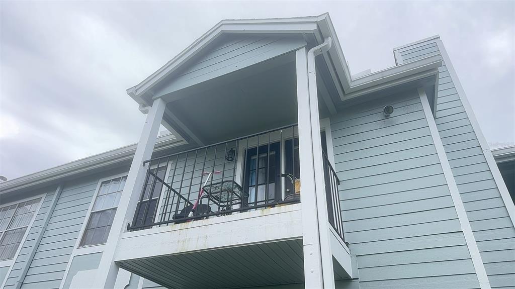 A low-angle exterior view of a light blue building with a second-story balcony — 2550 N ALAFAYA TRAIL UNIT 5203, ORLANDO, FL