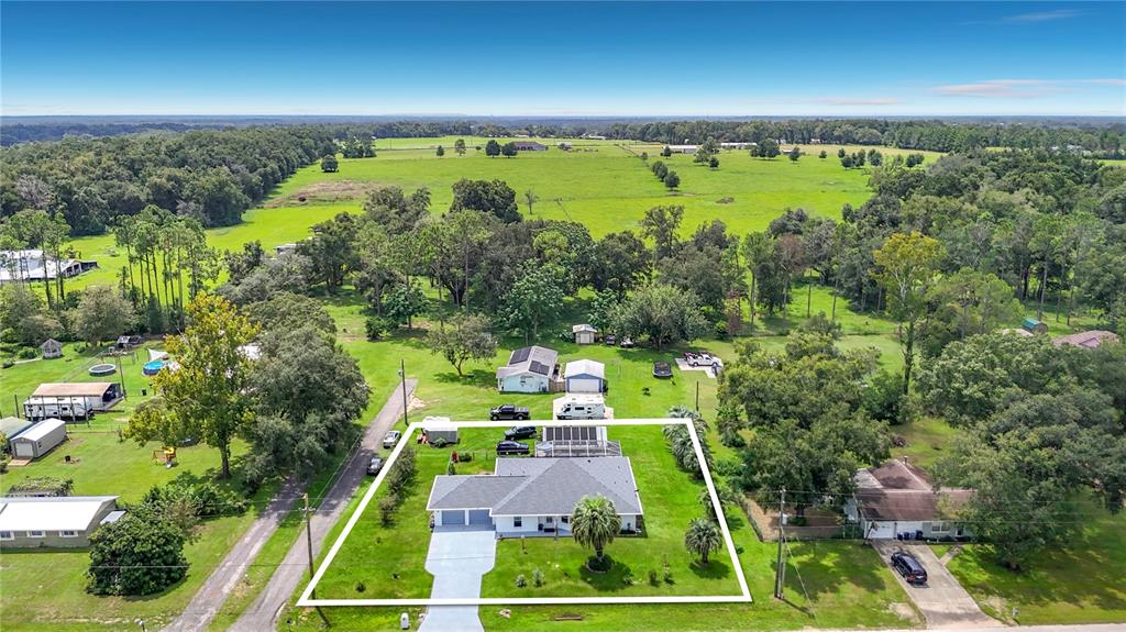 An aerial view shows a single-story house with a grey roof and a paved driveway — 40312 SUNBURST DRIVE, DADE CITY, FL