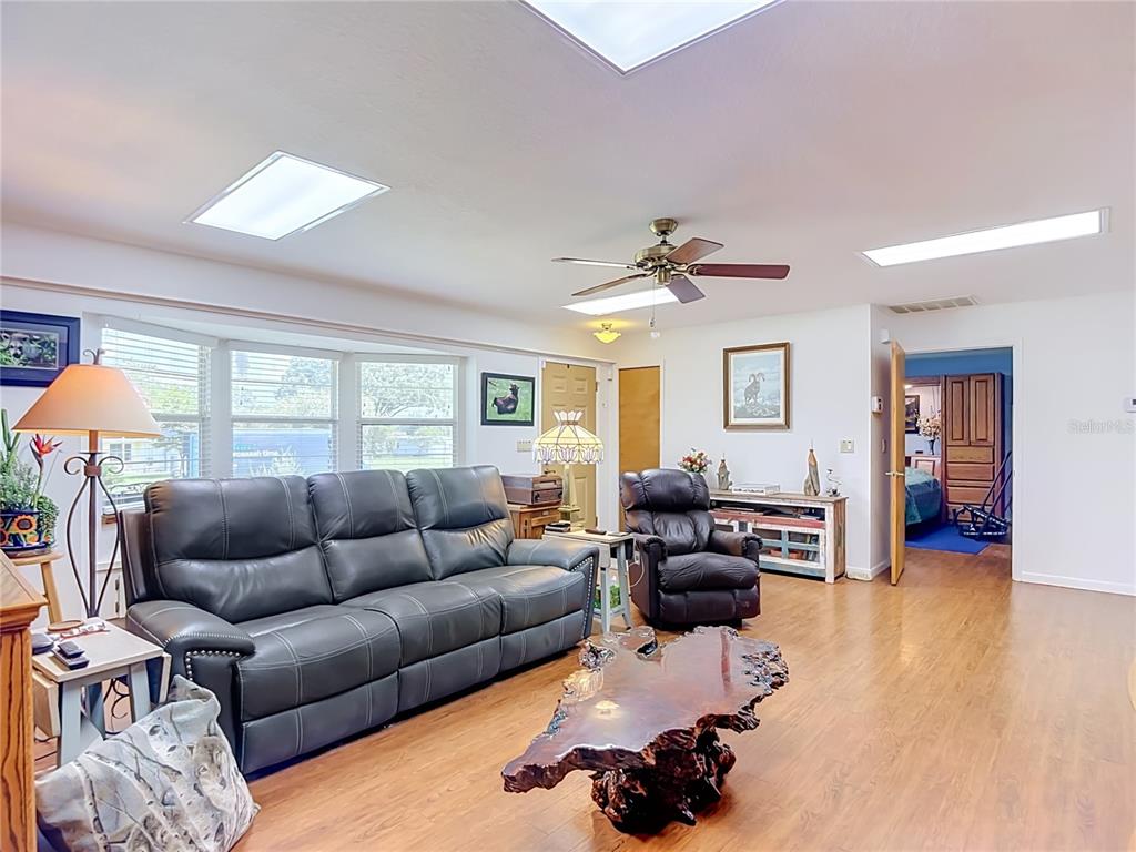 A living room features a dark leather sofa, a live-edge coffee table, and skylights — 40312 SUNBURST DRIVE, DADE CITY, FL
