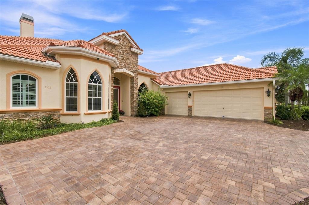 A single-story house with a tile roof, stone accents, and a paved driveway — 5102 DELACROIX DRIVE, BROOKSVILLE, FL