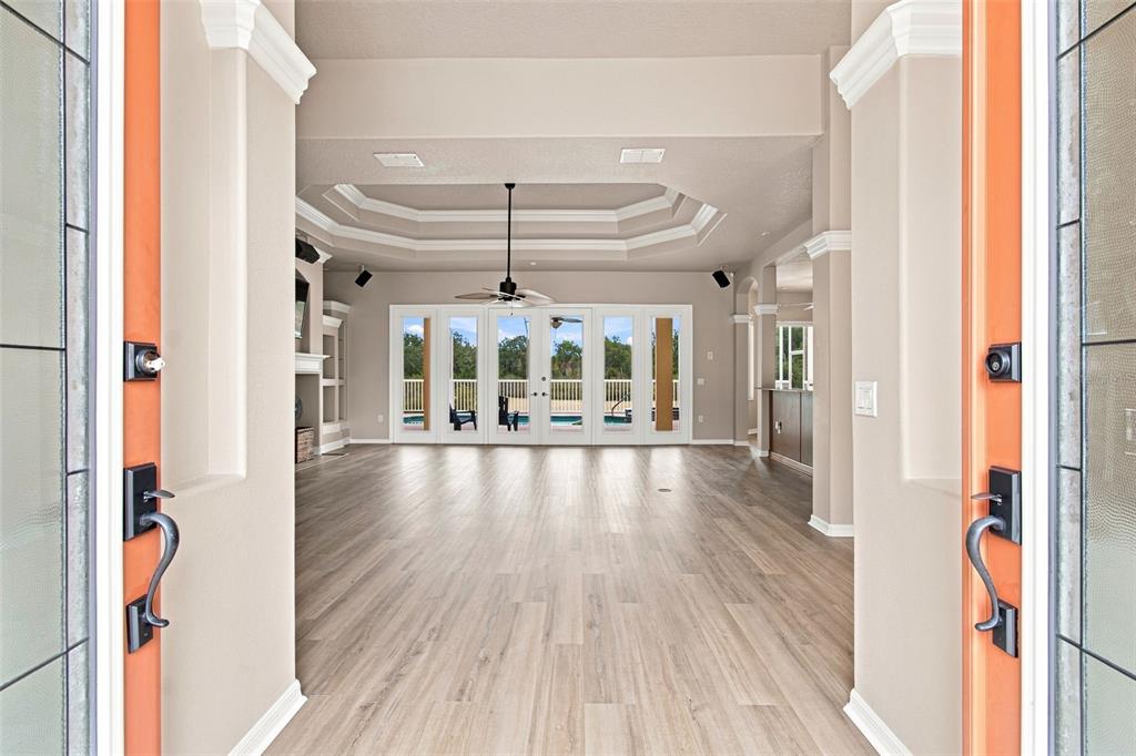 A view through an open doorway into a living room with light wood-look flooring — 5102 DELACROIX DRIVE, BROOKSVILLE, FL