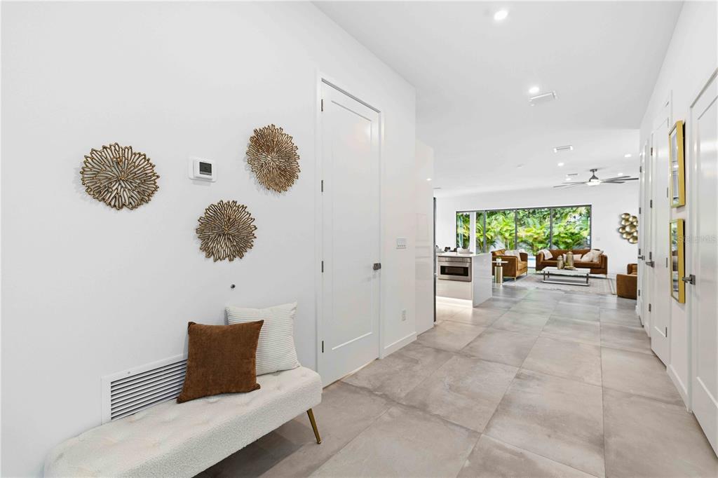 A white hallway with a bench leads to an open-concept living area with tile floors — 1671 ARLINGTON STREET, SARASOTA, FL