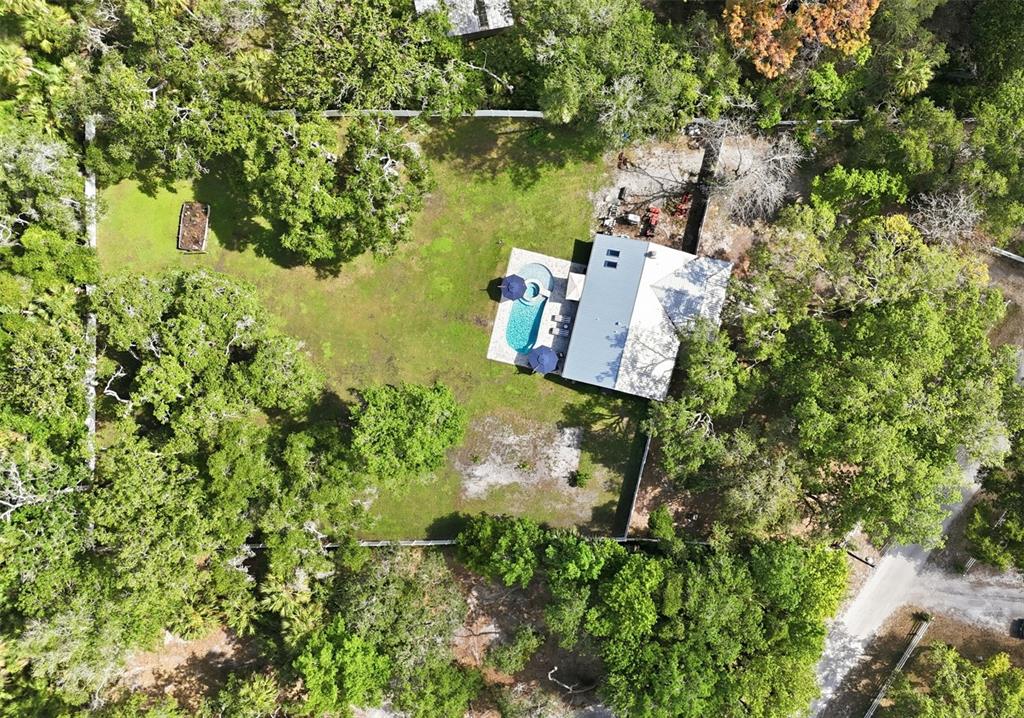 An aerial view of a house with a pool and patio in a wooded lot — 18909 JEBERT DRIVE, HUDSON, FL