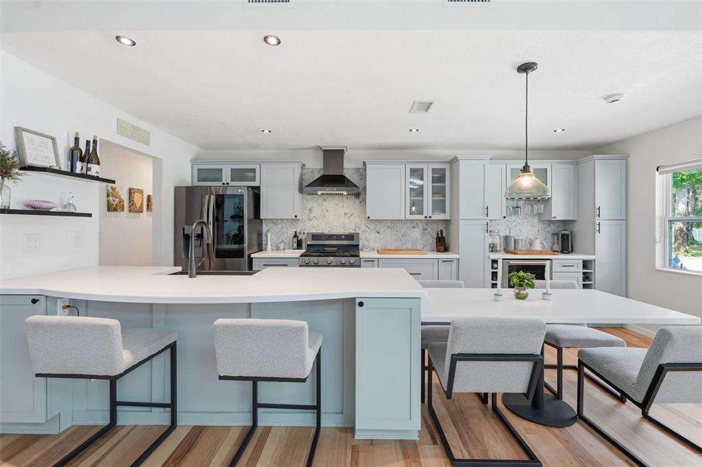 A kitchen features light blue cabinets, white countertops, a breakfast bar, and a dining area — 18909 JEBERT DRIVE, HUDSON, FL