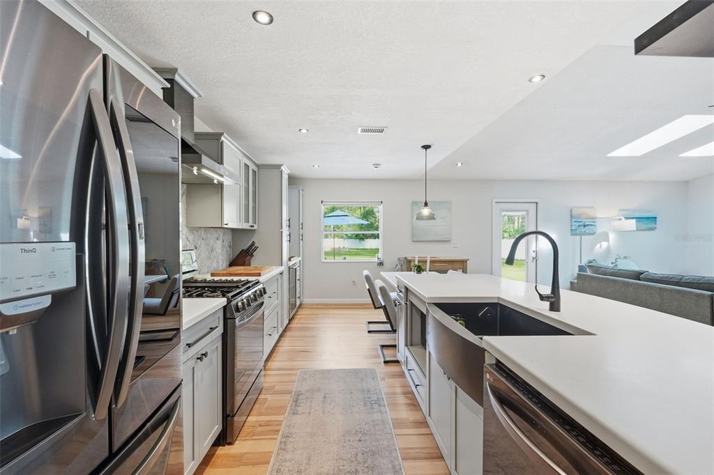 A modern kitchen features light gray cabinets, stainless steel appliances, and a large farmhouse sink — 18909 JEBERT DRIVE, HUDSON, FL