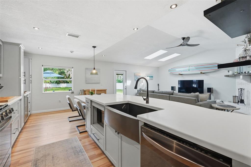 A modern kitchen features a large farmhouse sink, white countertops, and light wood flooring — 18909 JEBERT DRIVE, HUDSON, FL