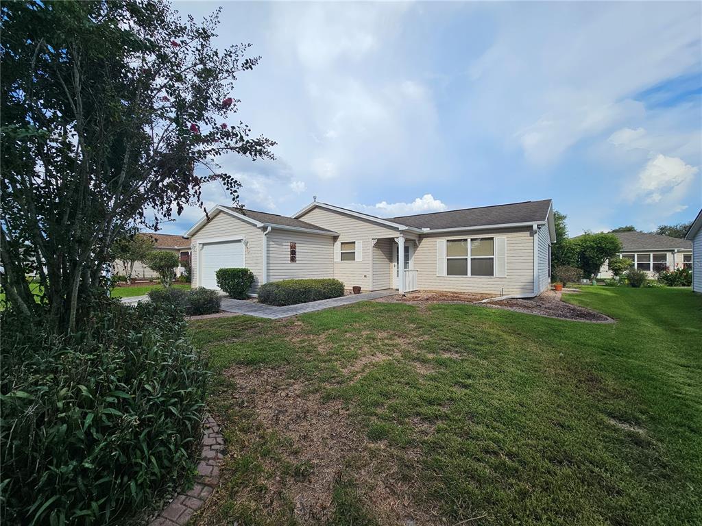 A single-story house with light-colored siding, a garage, and a front lawn — 945 CANDLER PLACE, THE VILLAGES, FL