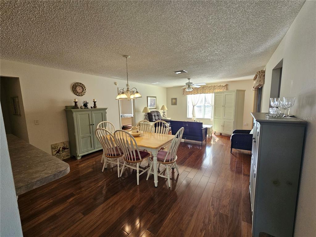 A dining area with a wooden table and chairs sits in an open-concept living space — 945 CANDLER PLACE, THE VILLAGES, FL