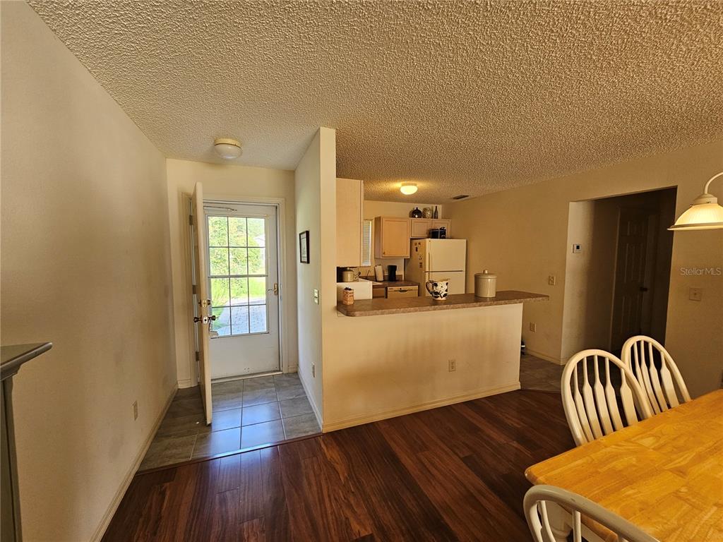 An interior view showing a dining area, a kitchen with a breakfast bar, and an entryway — 945 CANDLER PLACE, THE VILLAGES, FL