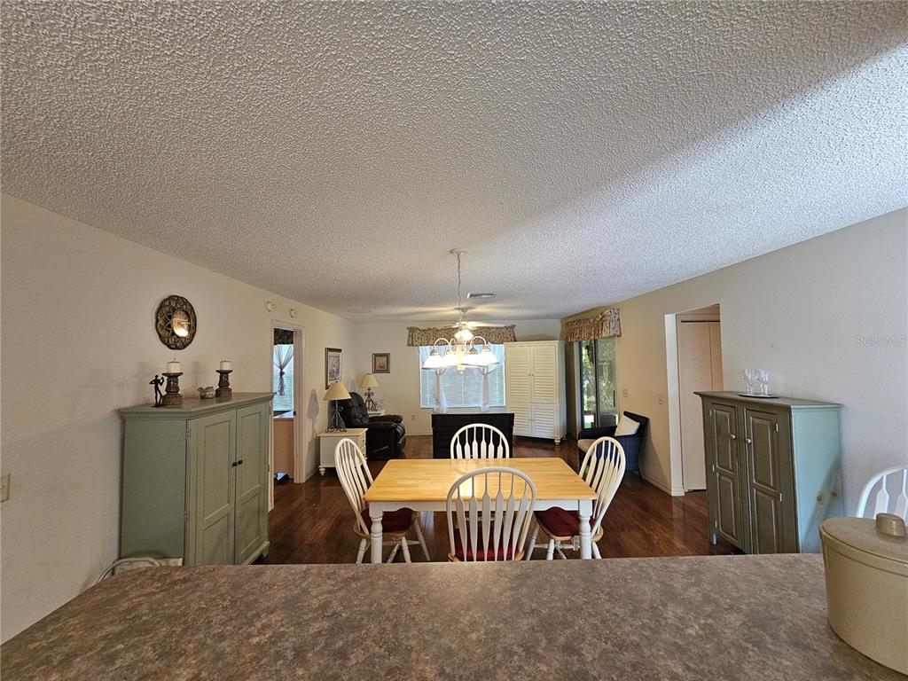 A dining room with a wooden table, white chairs, and two sage green cabinets — 945 CANDLER PLACE, THE VILLAGES, FL