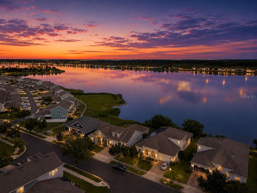 An aerial view shows a suburban house with a paved driveway and a lake behind it — 589 BLUE CYPRESS DRIVE, GROVELAND, FL
