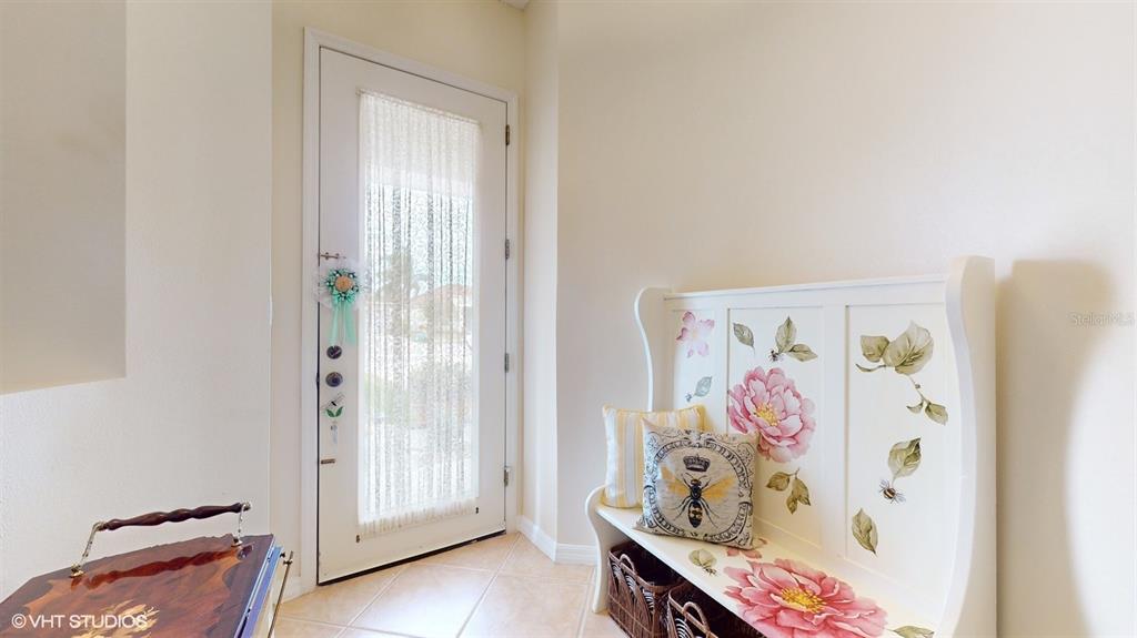 An entryway features a white door with a sheer curtain and a floral-painted wooden bench — 321 CRESSA CIRCLE, COCOA, FL