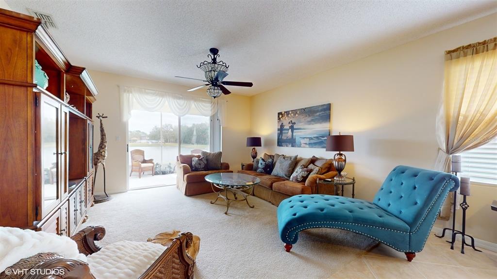 A living room features a blue chaise lounge, brown sofa, and sliding glass doors — 321 CRESSA CIRCLE, COCOA, FL