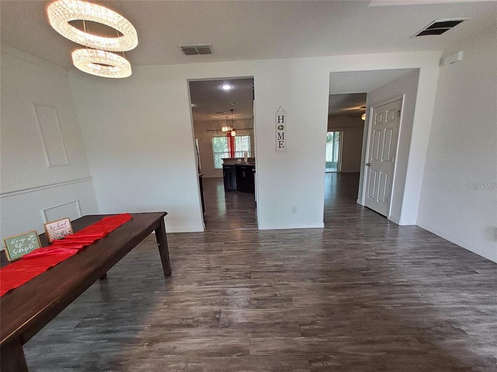 A dining area with wood-look flooring, a modern chandelier, and two doorways leading to other rooms — 355 GRANADA BOULEVARD, DAVENPORT, FL