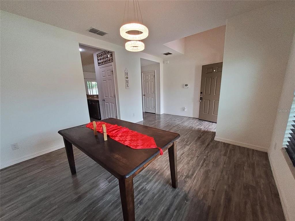 A dining area features a wooden table, a modern light fixture, and gray wood-look flooring — 355 GRANADA BOULEVARD, DAVENPORT, FL