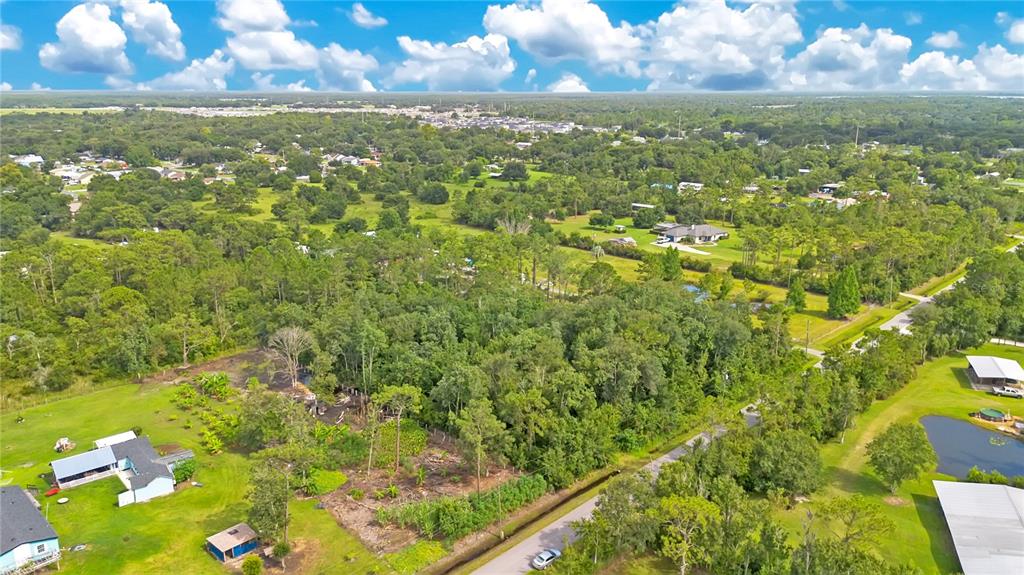 An aerial view shows a wooded lot surrounded by residential properties, a road, and ponds — 3641 PACKARD AVENUE, ST CLOUD, FL