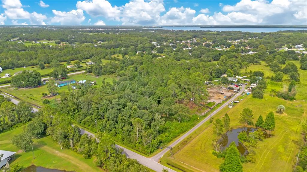 An aerial view shows a wooded lot bordered by roads with a pond nearby — 3641 PACKARD AVENUE, ST CLOUD, FL