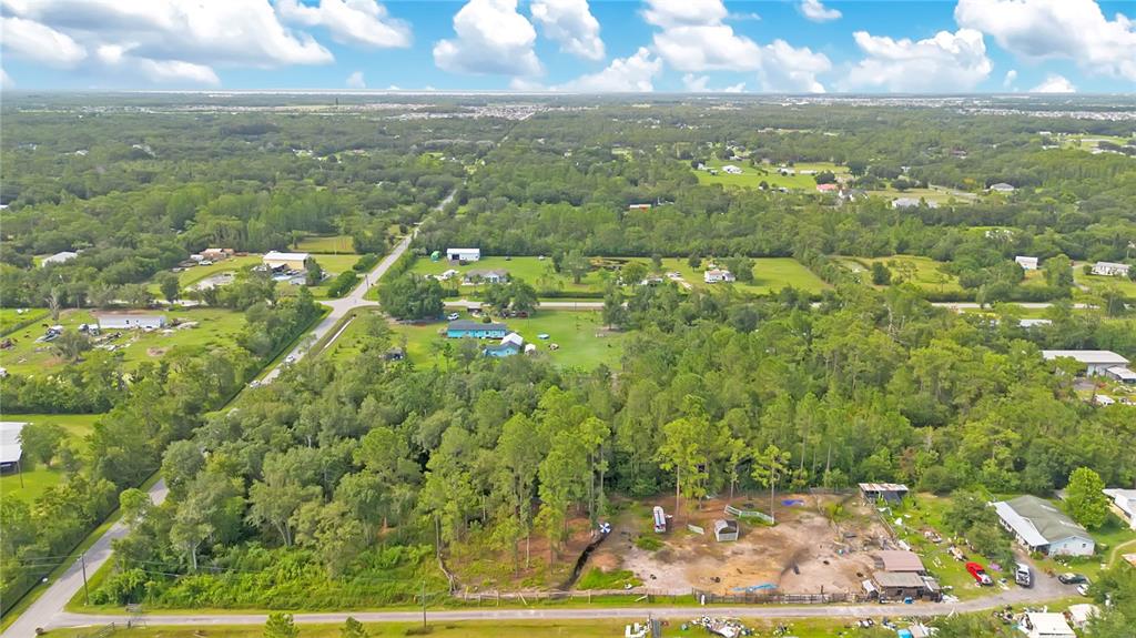 An aerial view shows a rural property with wooded areas, open land, and several small buildings — 3641 PACKARD AVENUE, ST CLOUD, FL