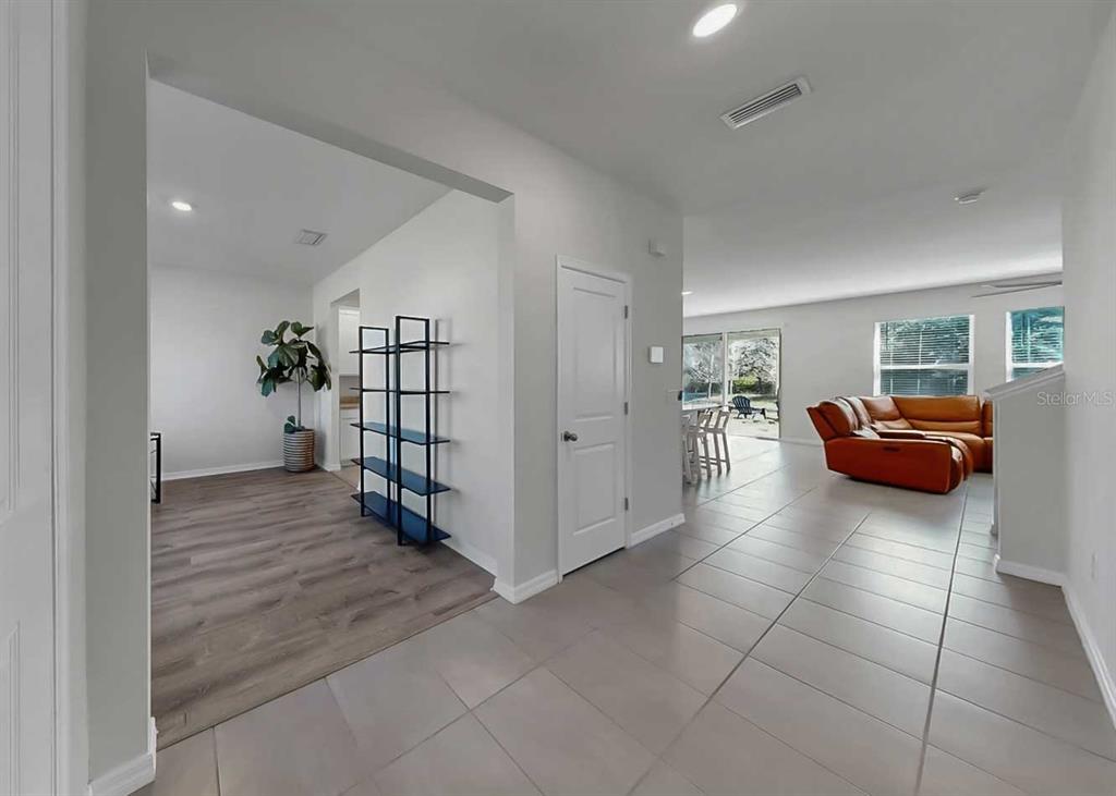 An interior view shows a tiled entryway transitioning to wood-look flooring with a living area — 16454 WOODSIDE GLEN, PARRISH, FL