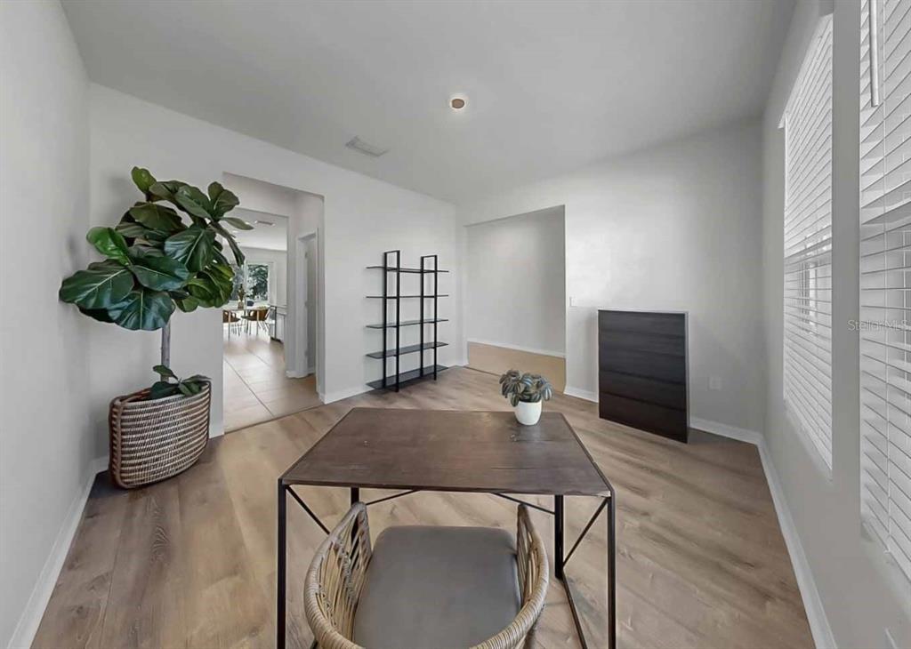 A bright room features light wood-look flooring, a dark table, a tall shelf, and a plant — 16454 WOODSIDE GLEN, PARRISH, FL