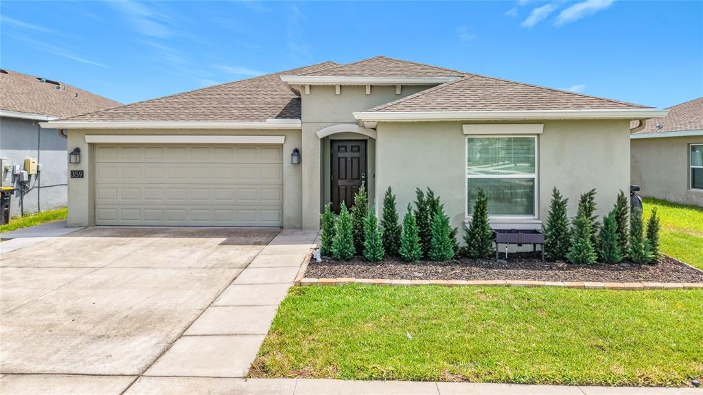 A single-story house with a beige stucco exterior, a two-car garage, and a landscaped yard — 359 MACARTHUR STREET, BARTOW, FL