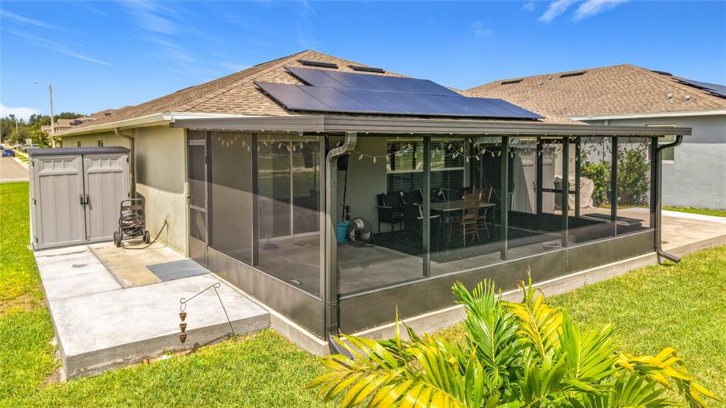A screened-in patio with solar panels on the roof and a storage shed outside — 359 MACARTHUR STREET, BARTOW, FL