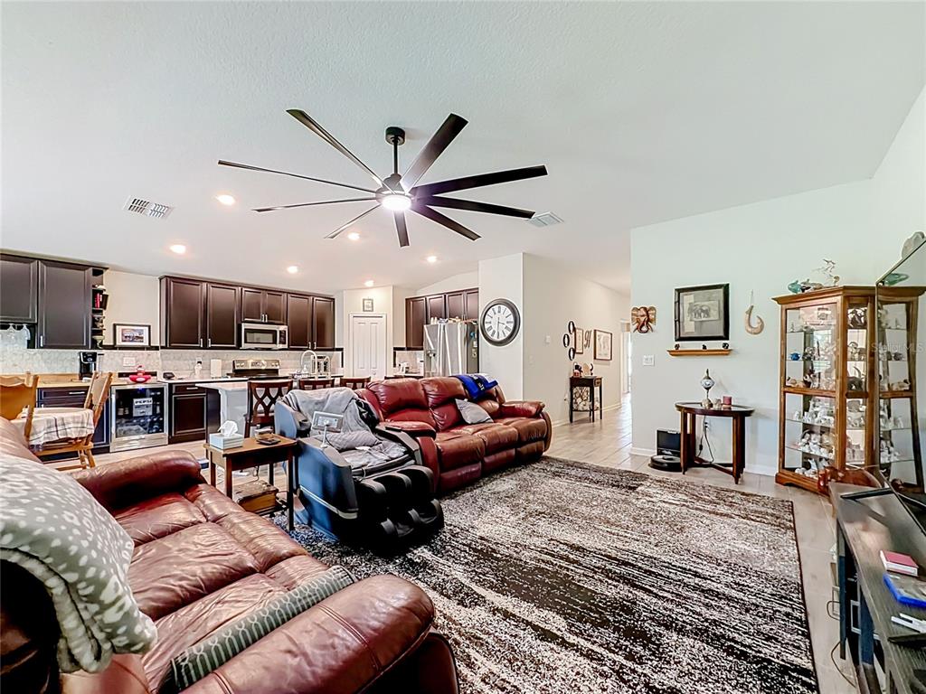 A living room with red leather sofas, a large area rug, and an open kitchen — 359 MACARTHUR STREET, BARTOW, FL