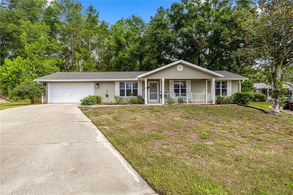 A single-story house with light green siding, a front porch, and an attached two-car garage — 8137 SW 117TH LOOP, OCALA, FL