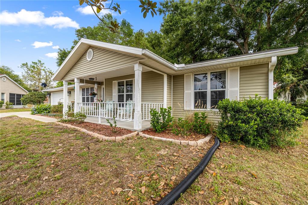 A single-story house with light green siding, a covered front porch, and a black downspout — 8137 SW 117TH LOOP, OCALA, FL