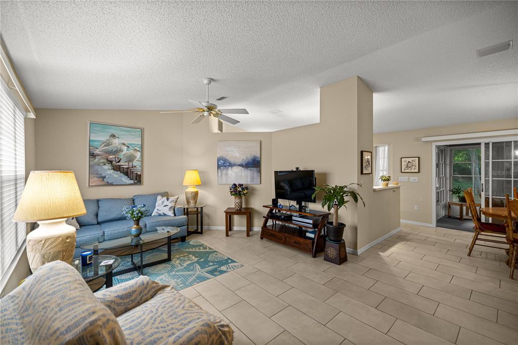 A living room with tile floors, a blue sofa, and a television on a wooden stand — 8137 SW 117TH LOOP, OCALA, FL