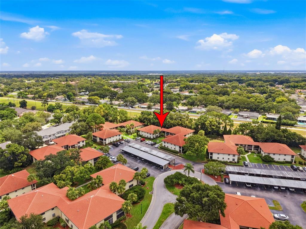 An aerial view shows a multi-story apartment complex with red tile roofs and parking lots — 1309 HAMMOCK PINE BOULEVARD UNIT 1309, CLEARWATER, FL