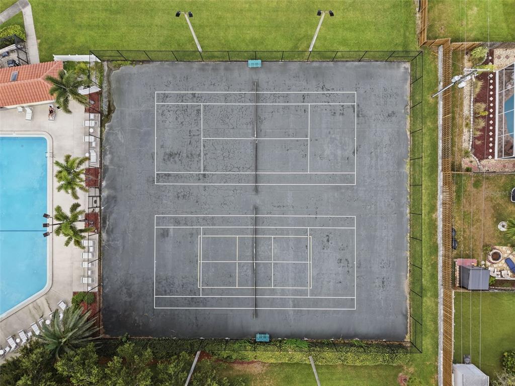 An aerial view shows two tennis courts adjacent to a swimming pool and patio area — 1309 HAMMOCK PINE BOULEVARD UNIT 1309, CLEARWATER, FL